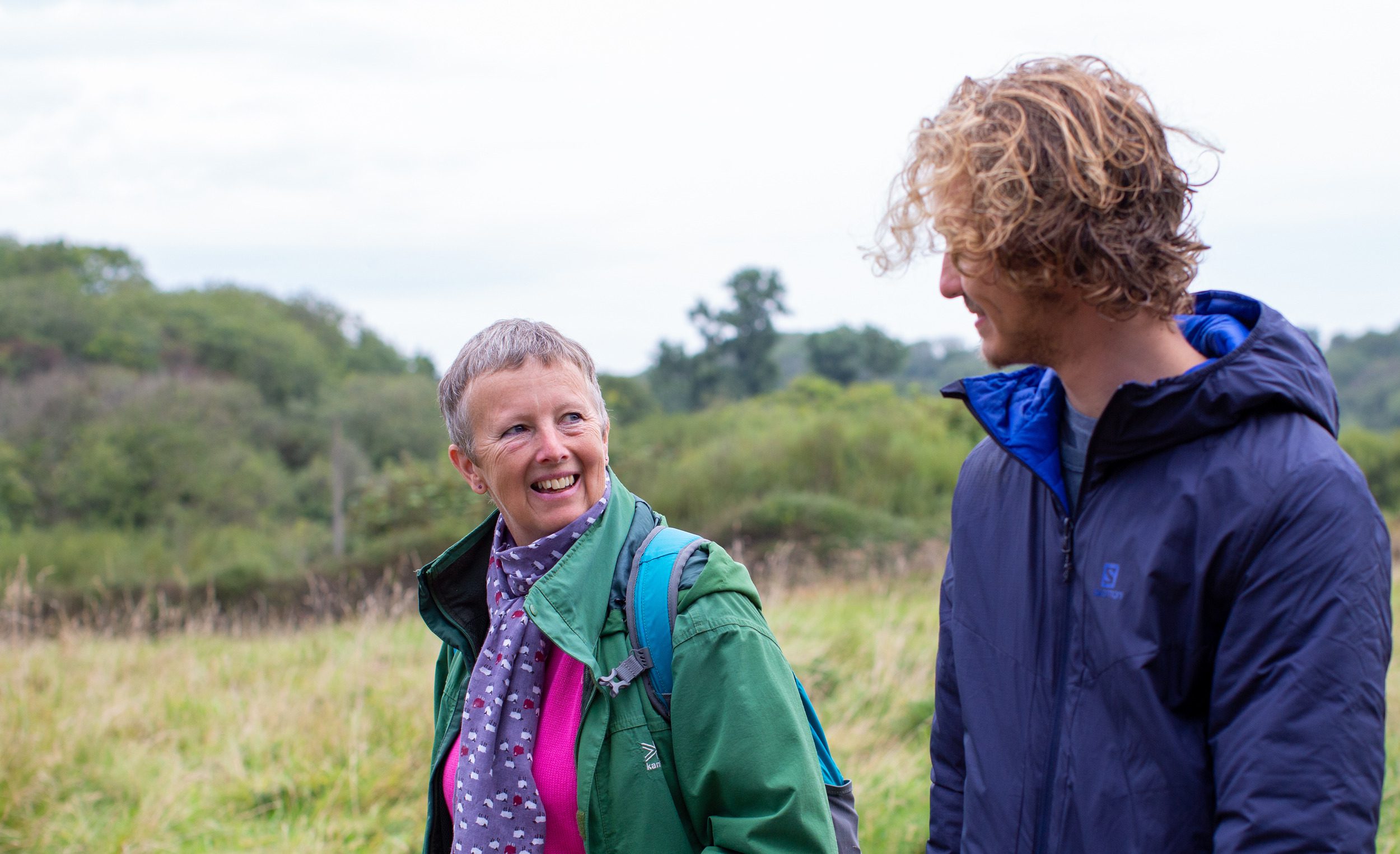 A woman walking with a young man among nature