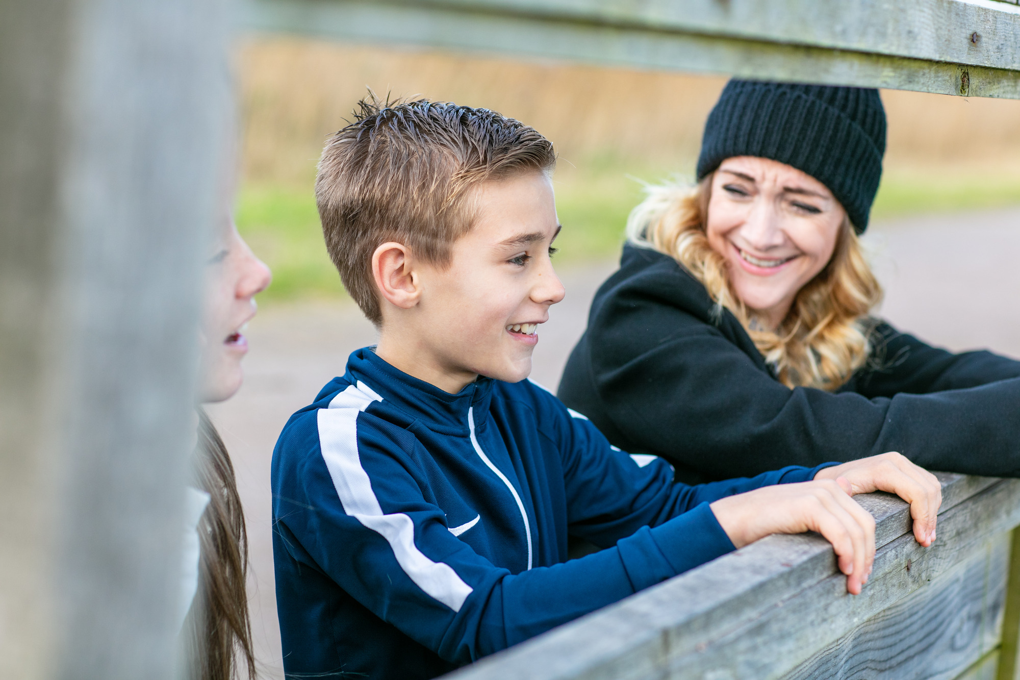 A woman and a boy standing by the fence and smiling