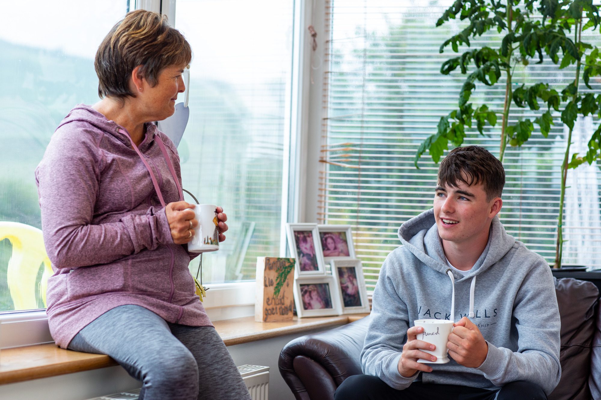 A woman and a young man sitting in a room drinking tea and talking