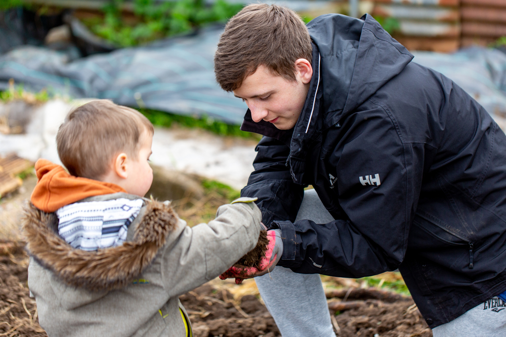 A man and a small boy in the garden playing with soil