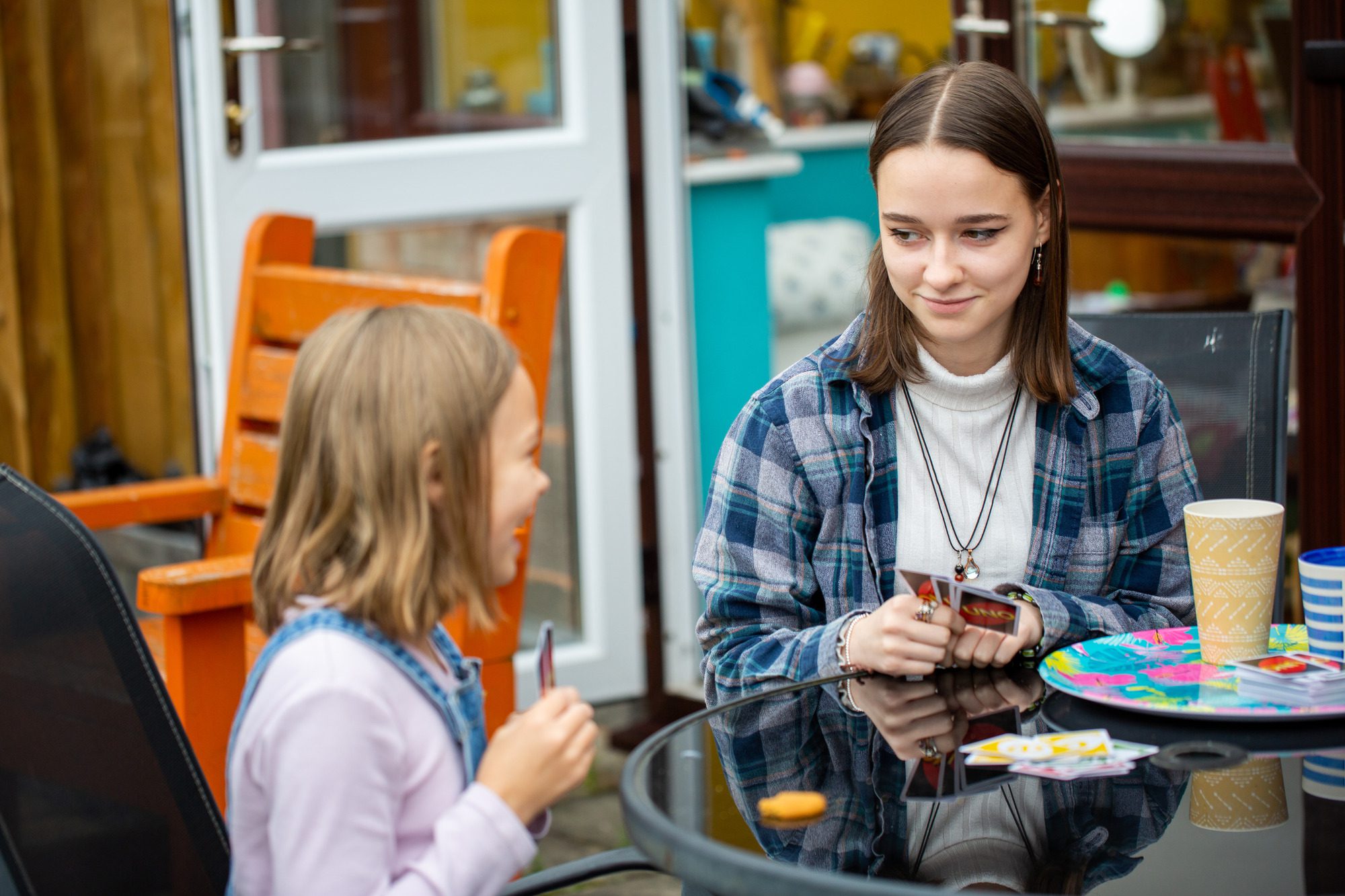 A teenage girl and a young girl playing cards
